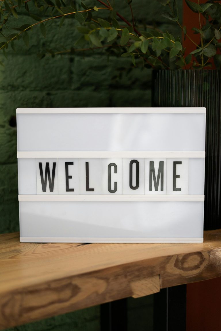 Lightbox with 'Welcome' text on a wooden table against a green wall.